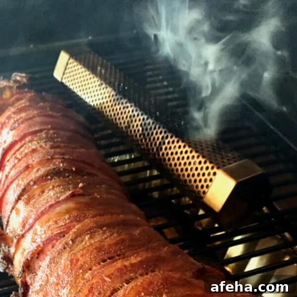 A smoke tube on a grill with some meat.