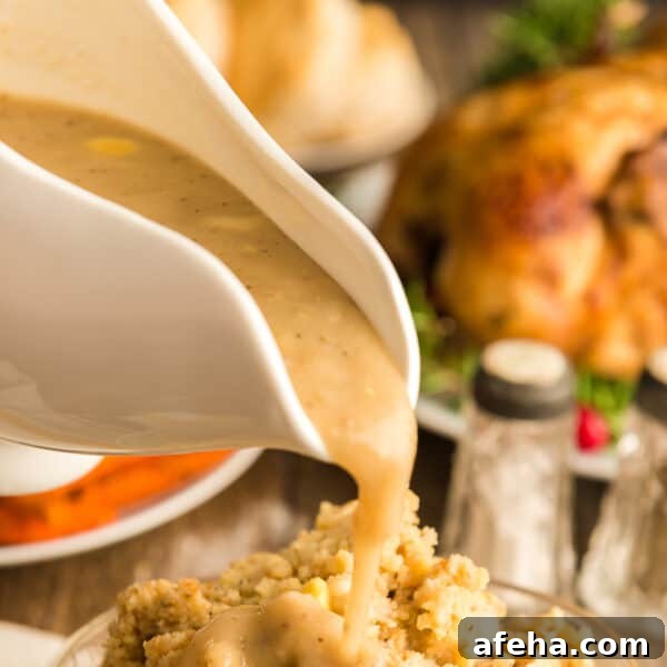 A gravy boat full of gravy being poured on stuffing.