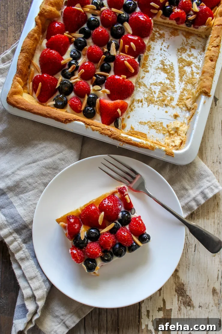 Fruit pizza square on plate with pan in background.