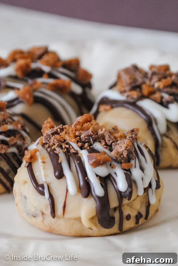 A white plate with toffee cookies on it that have chocolate drizzles and toffee candy on top.