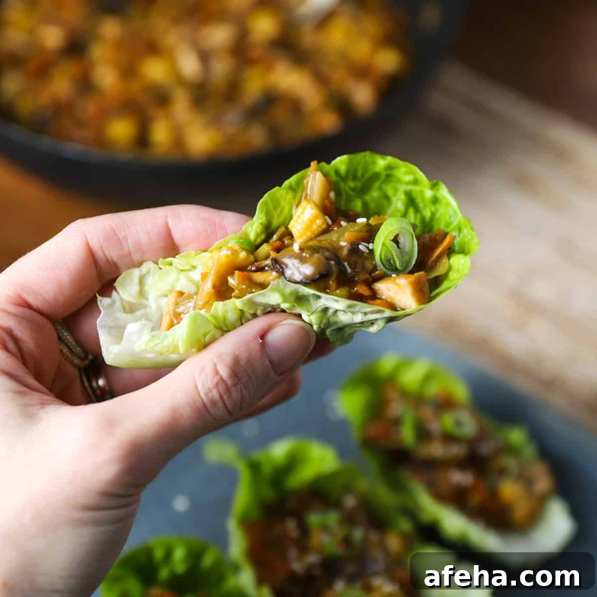 Vegan San Choy Bau Recipe: Flavorful Plant-Based Lettuce Wraps 12 Photo of a hand holding a lettuce leaf filled with vegan san choy bau filling.