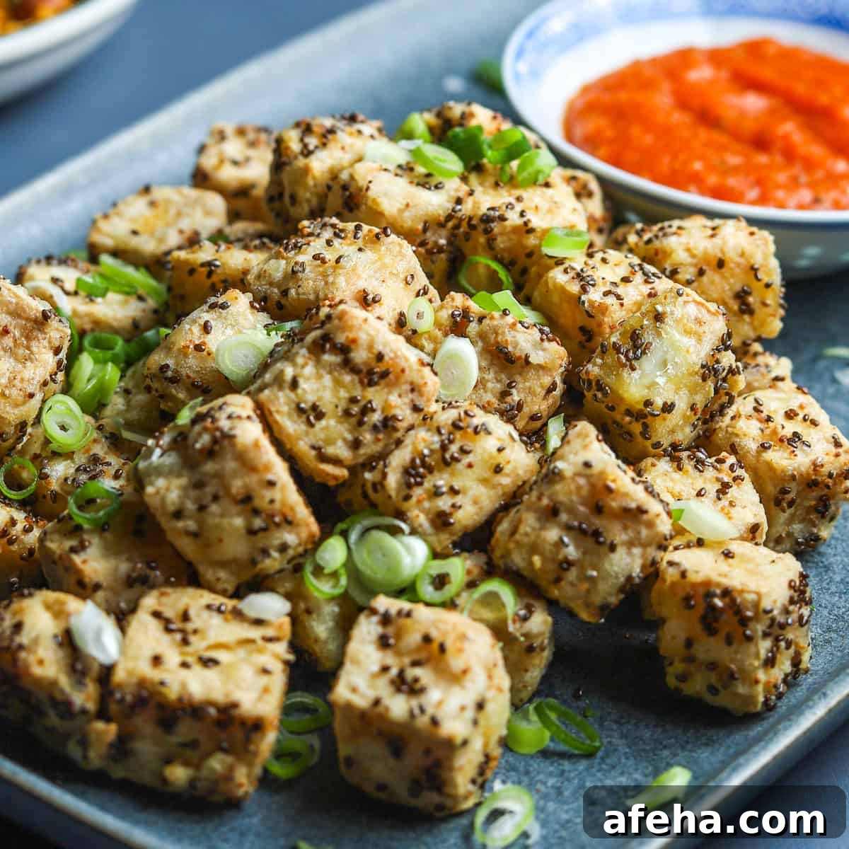 Vegan San Choy Bau Recipe: Flavorful Plant-Based Lettuce Wraps 15 photo of a blue oblong plate filled with crispy air fried tofu with spring onion sprinkled on top