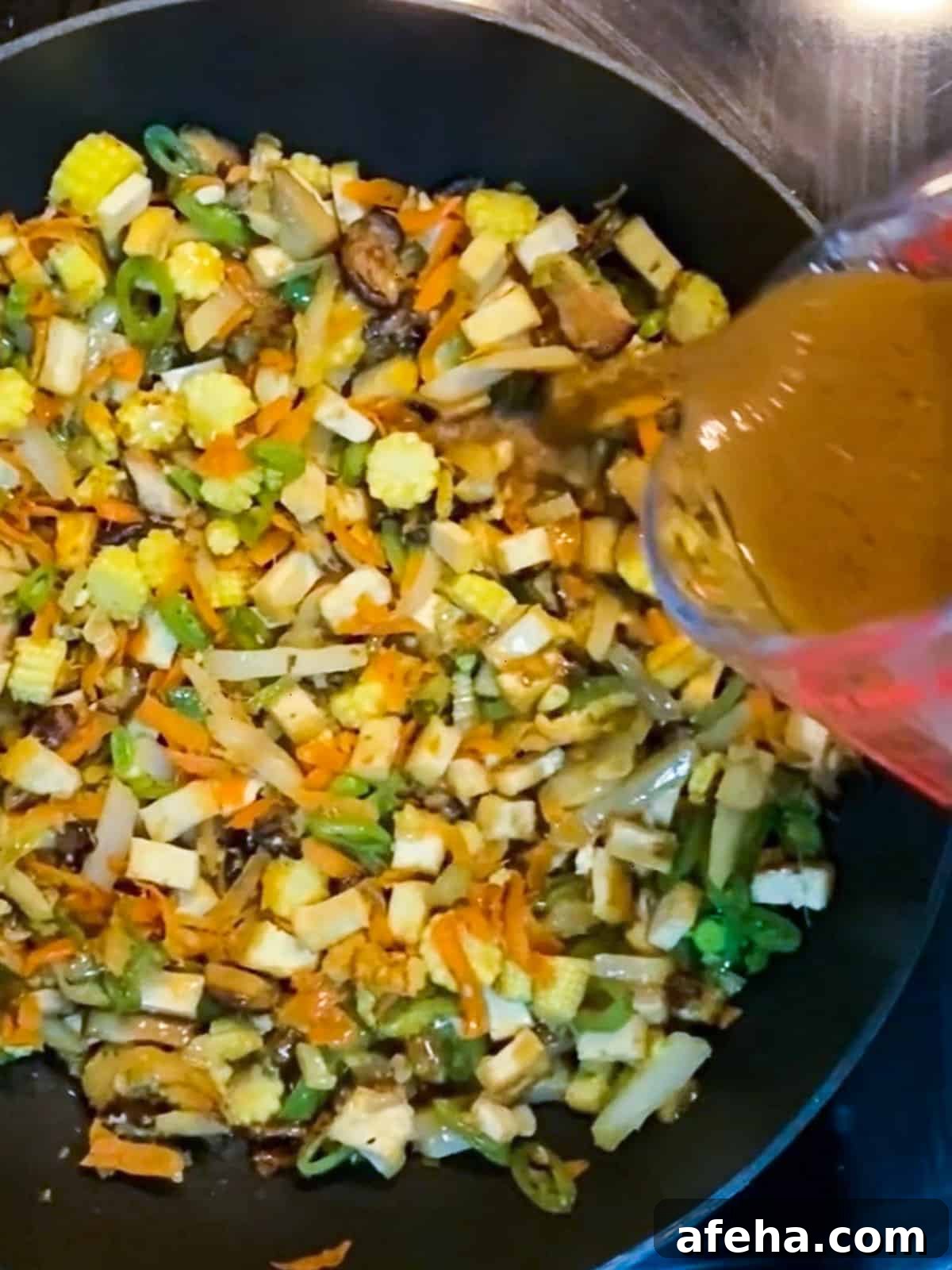 Vegan San Choy Bau Recipe: Flavorful Plant-Based Lettuce Wraps 9 Photo of sauce being added to the san choy bau mixture in the pan.