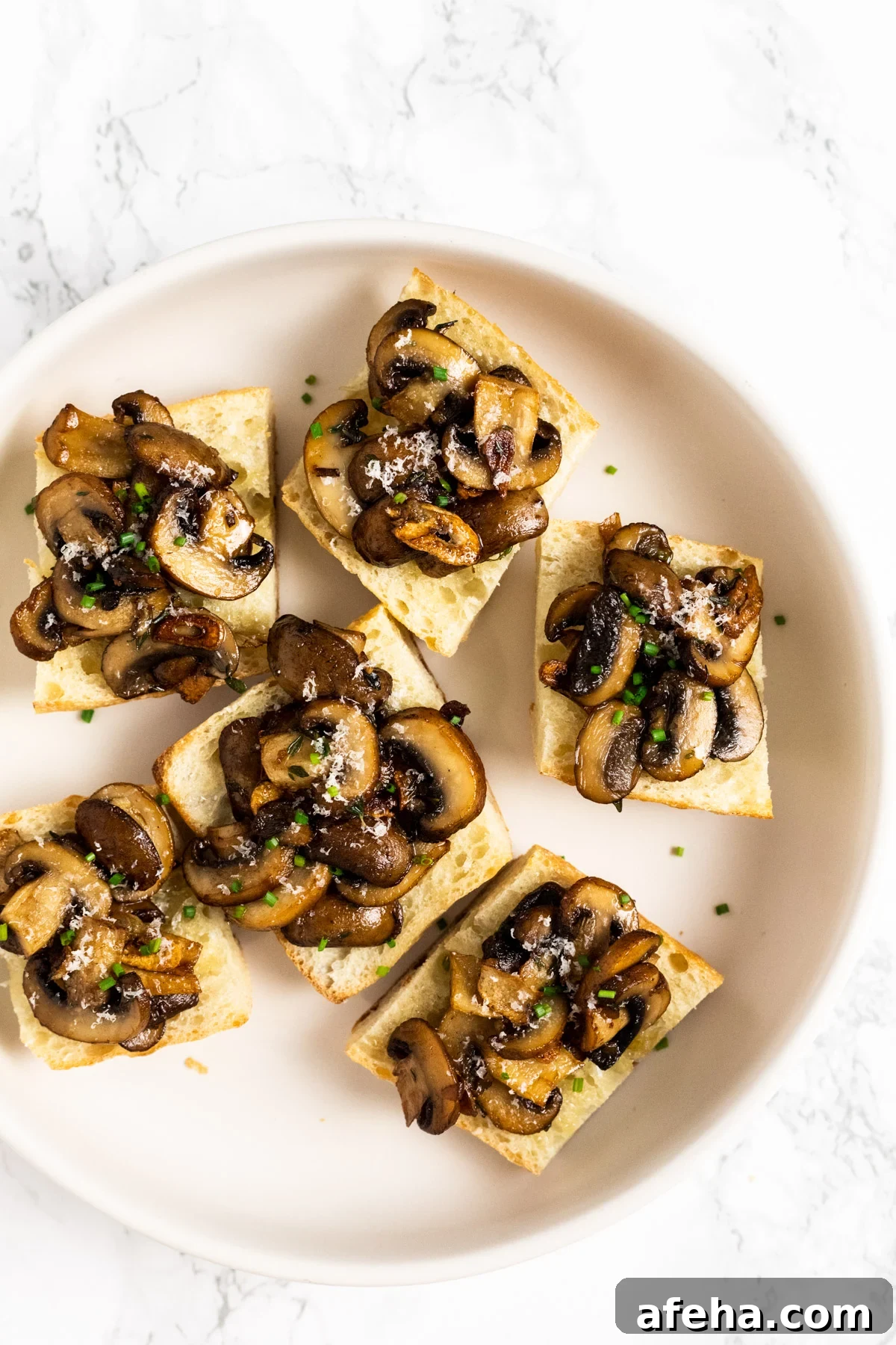 A top down view six pieces of mushroom bruschetta on a plate.