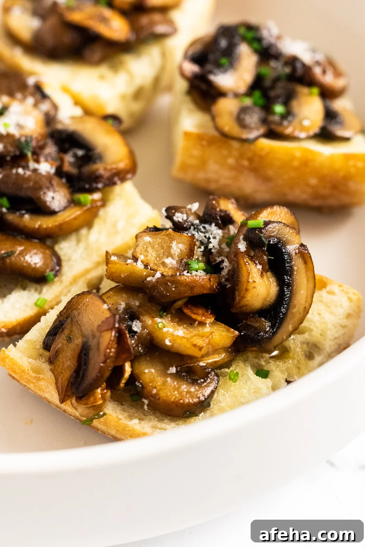 A close up side view of a piece of mushroom bruschetta on a plate.