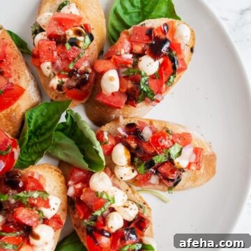A top down view of a plate of bruschetta with mozzarella garnished with fresh basil leaves.