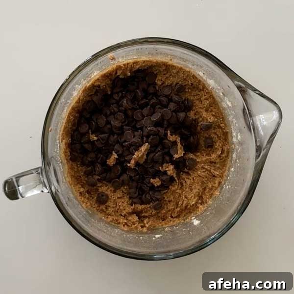 Gluten-free chocolate chip cookie dough with chocolate chips in a glass mixing bowl.