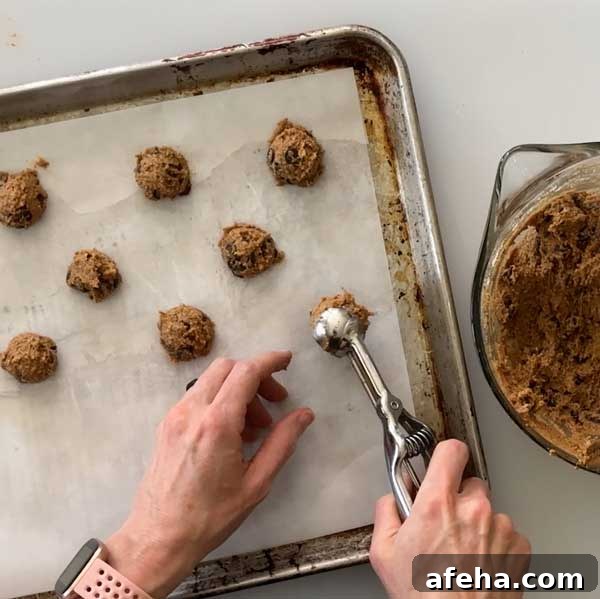 Scooping cookie dough on to a baking sheet using a small cookie scoop.