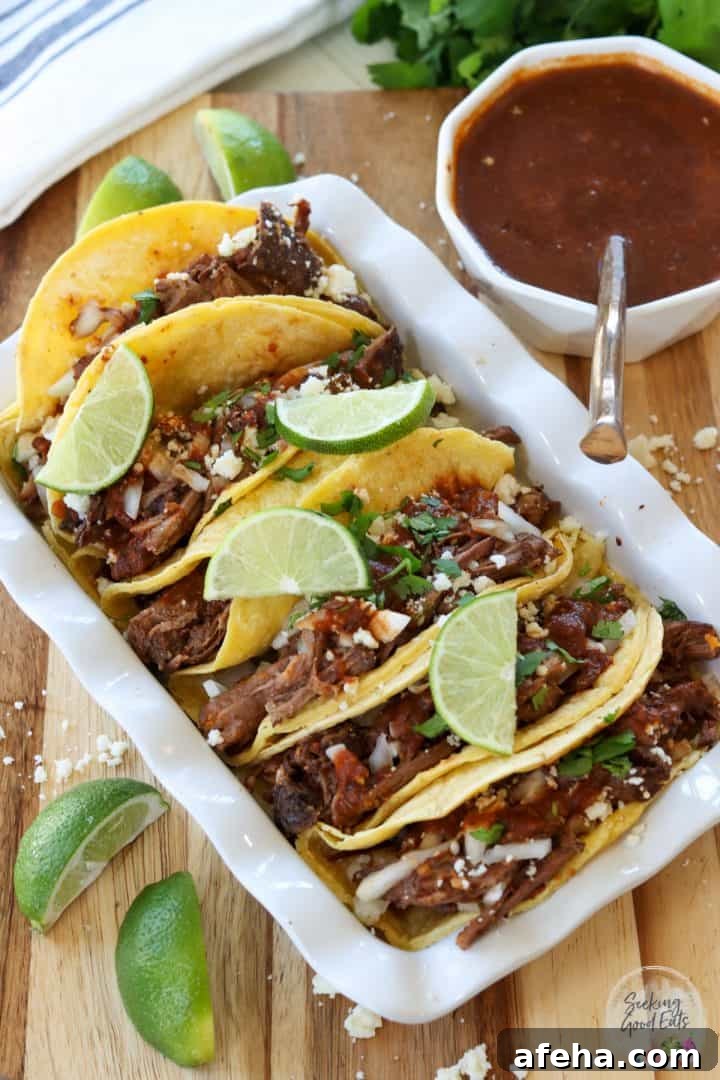 Birria Tacos with Rich Consommé: Where to Eat and How to Make Them 2 Birria tacos served with consomme and garnished with limes, cilantro, and queso fresco cheese.
