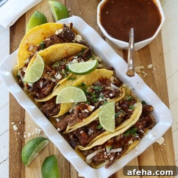 Birria Tacos with Rich Consommé: Where to Eat and How to Make Them 10 birria taco served on a white rectangular platter.