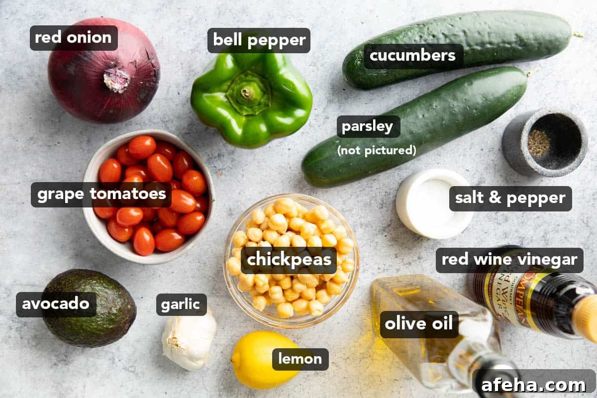 all ingredients for this chickpea salad recipe laid out: grape tomatoes, avocado, garlic, lemon, olive oil, red wine vinegar, salt & pepper, parsley, cucumbers, and bell pepper.