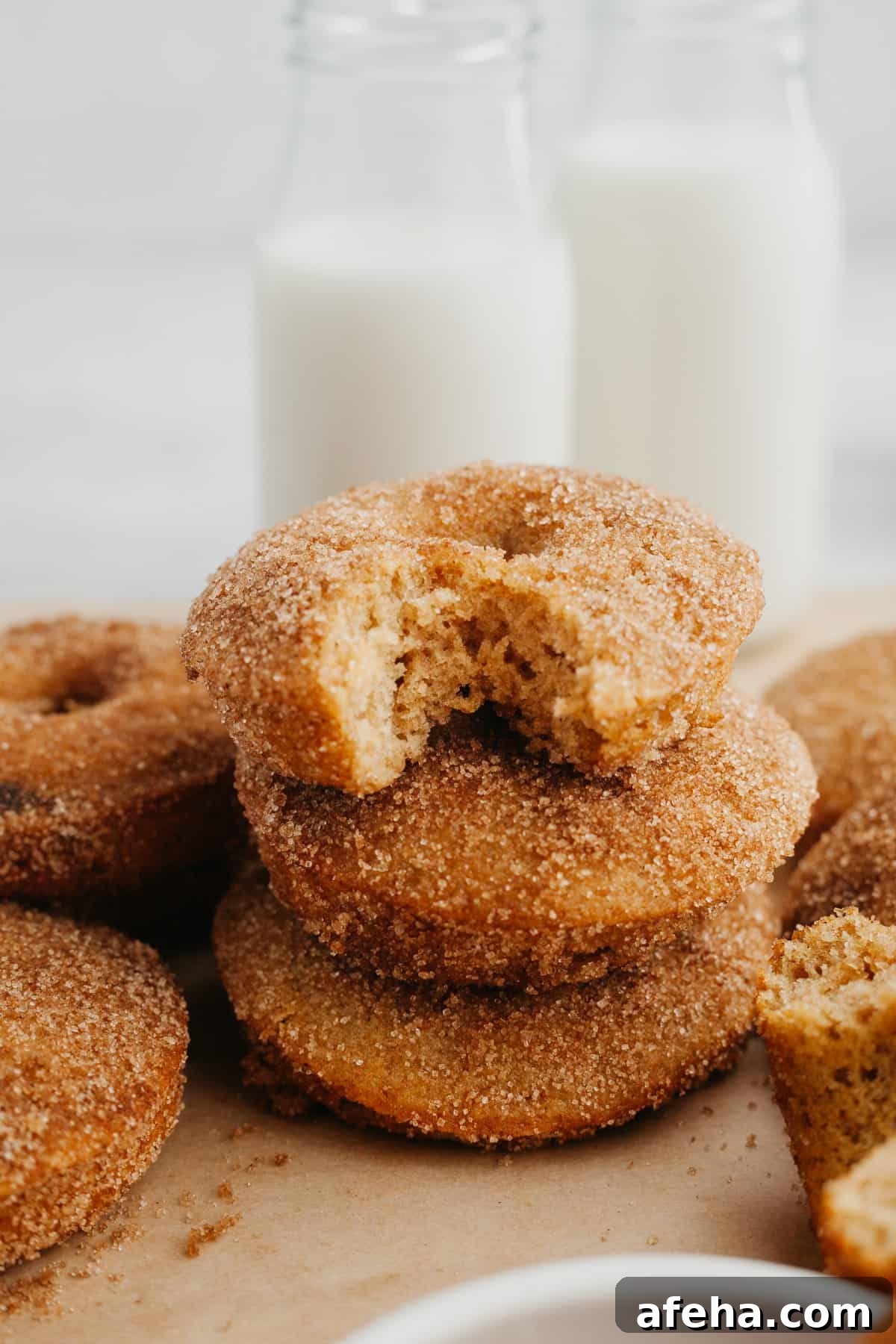 A stack of cinnamon donuts, the donut on top has a bite taken out of it.