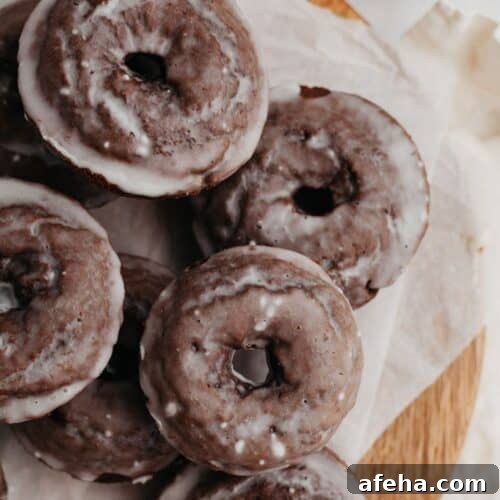 A pile of chocolate cake doughnuts on parchment paper.