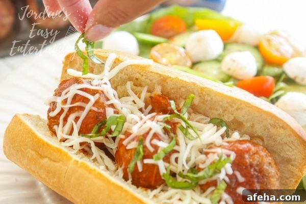 basil going on top of a Italian meatball sub sandwich