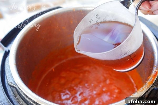 pouring beef broth into the pressure cooker