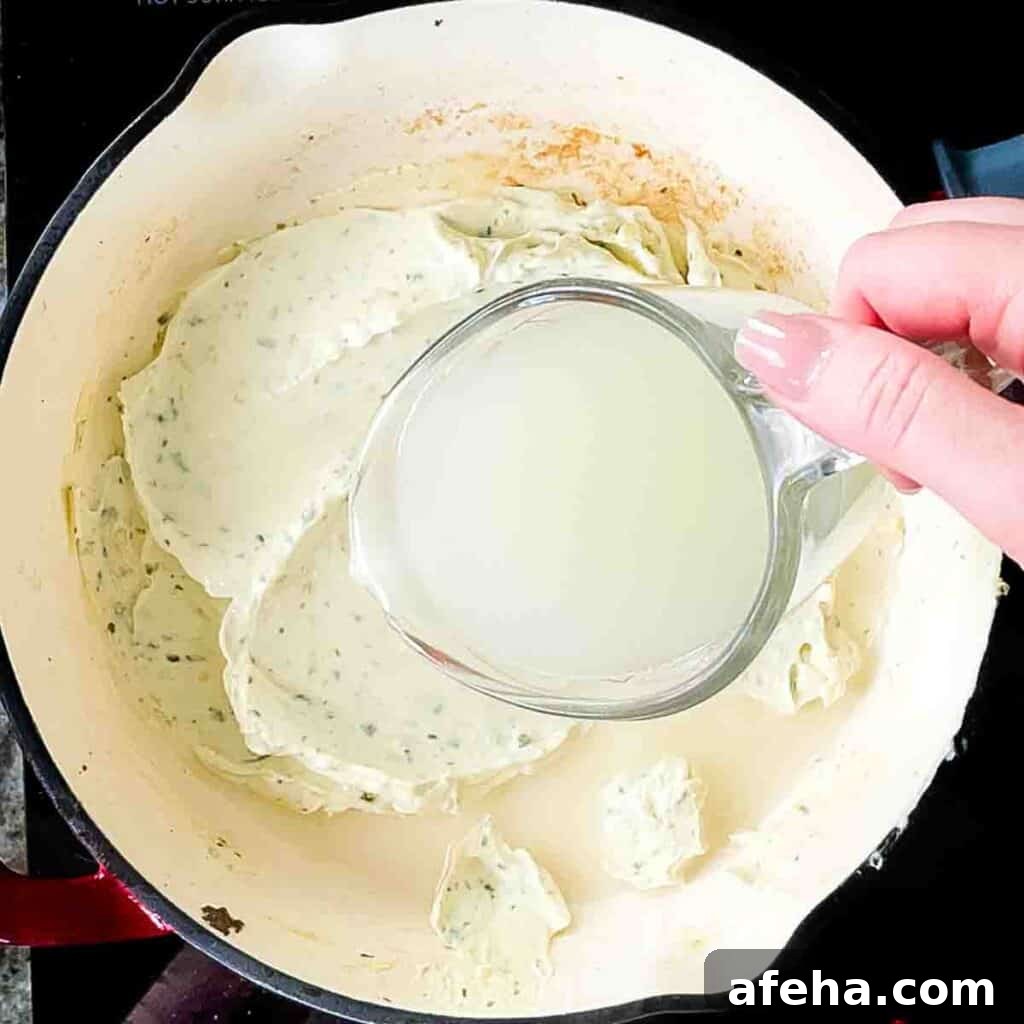 Cooking minced garlic in a skillet, then stirring in reserved pasta water to the Boursin cheese until it melts into a creamy sauce.
