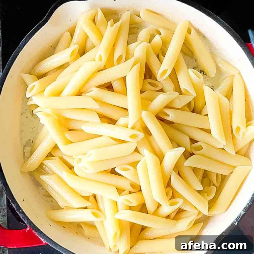 Tossing cooked pasta with the creamy Boursin cheese sauce and sautéed morel mushrooms in a large skillet.