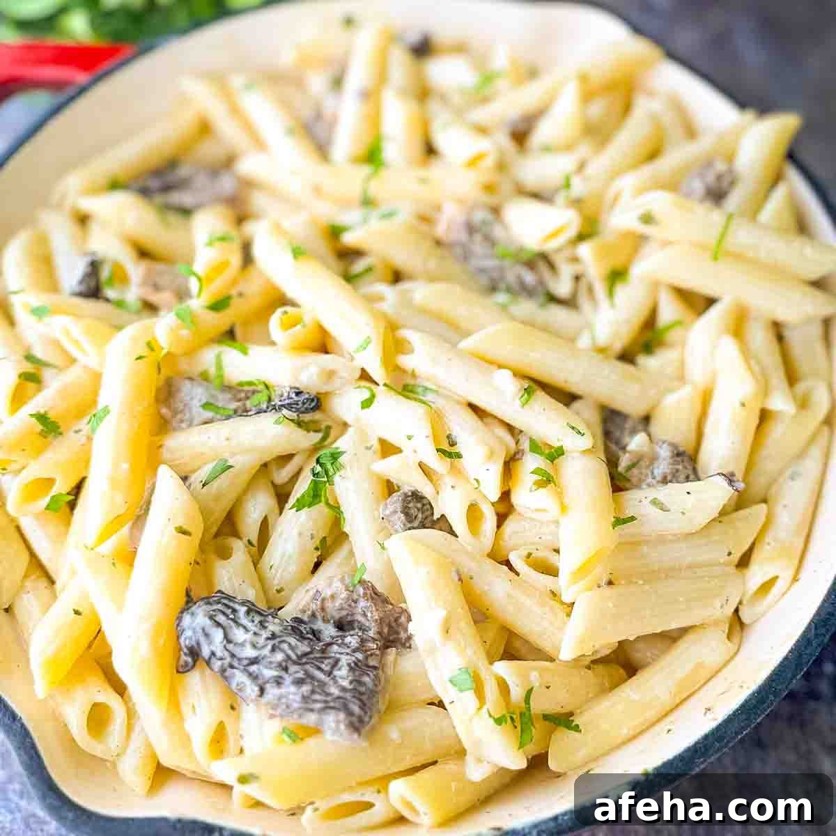 A large skillet filled with creamy Morel Mushroom Pasta, garnished with fresh parsley, ready to be served.