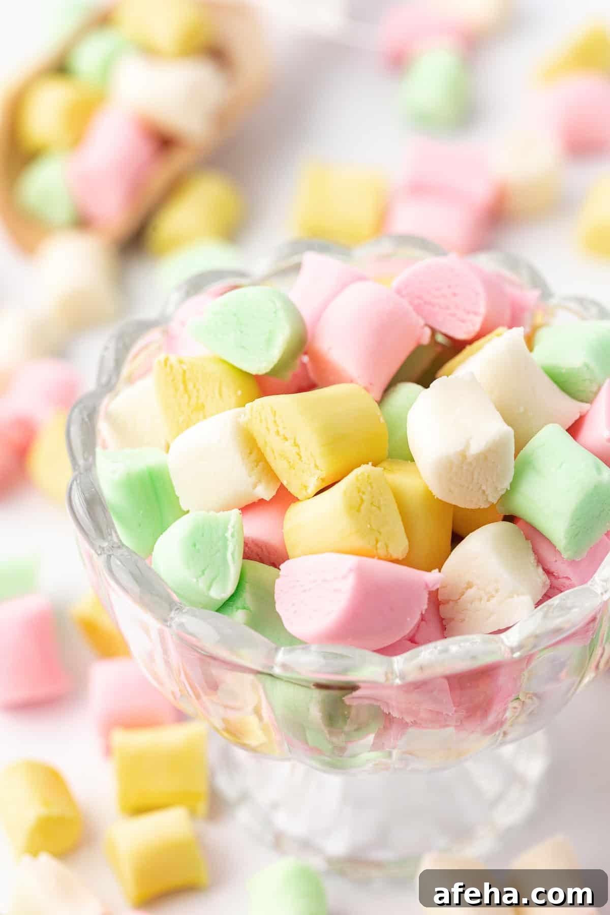 small glass trifle dish full of pink, yellow, white and green butter mints with more mints scattered around