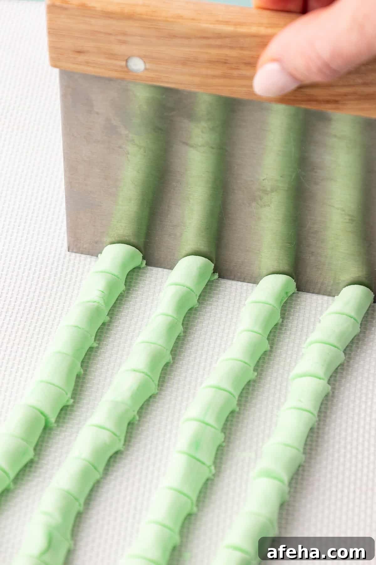four rows of green butter mint rope being cut into small pieces