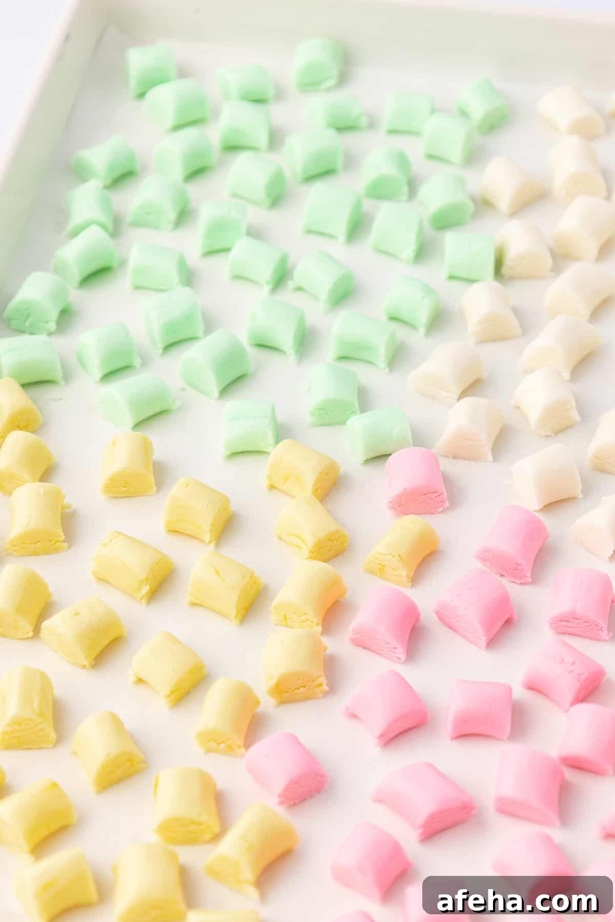 sheet pan with yellow, green, white and pink butter mints arranged in one layer on the pan