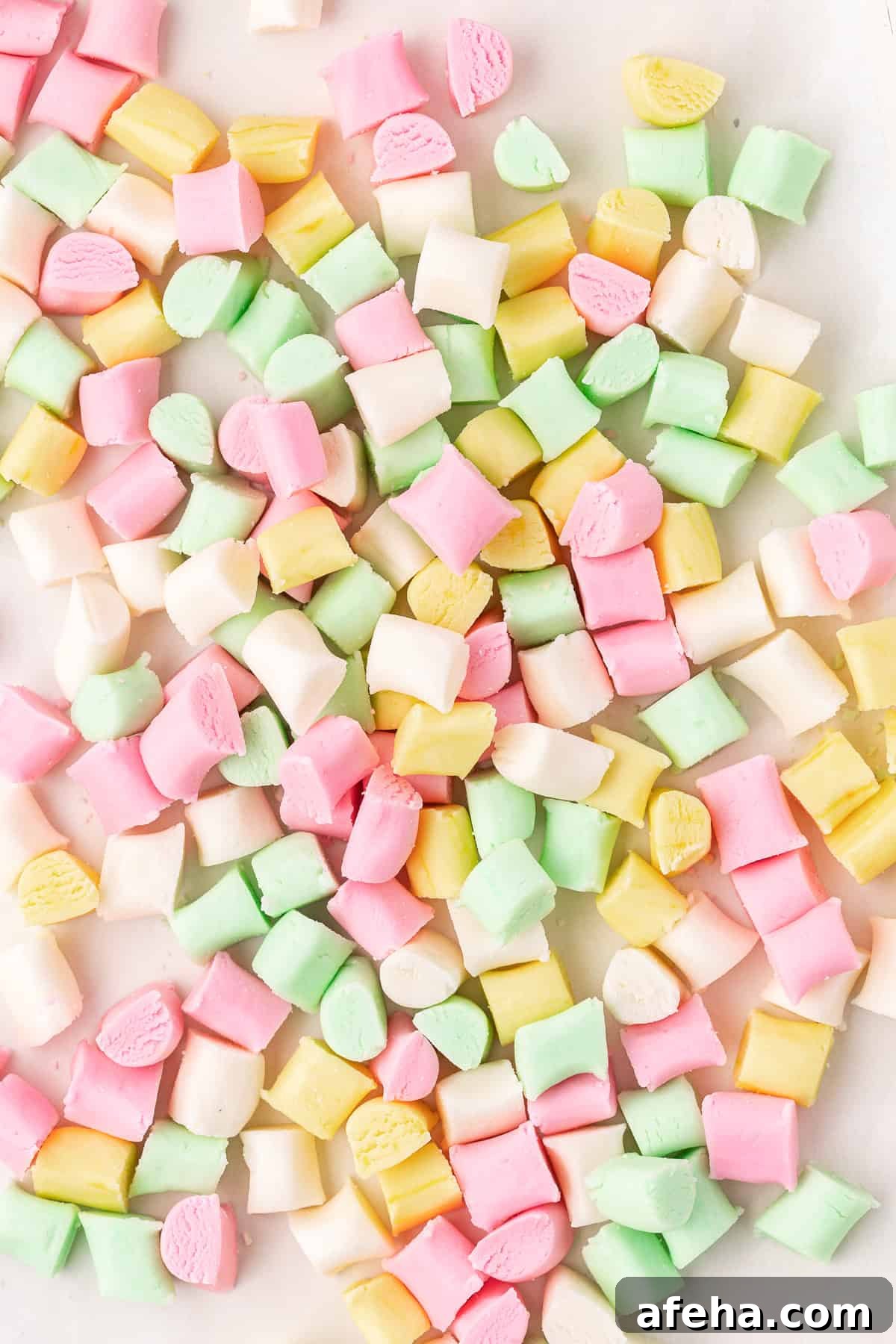 over head view of a large pile and scattered pink, yellow, green, and white butter mints