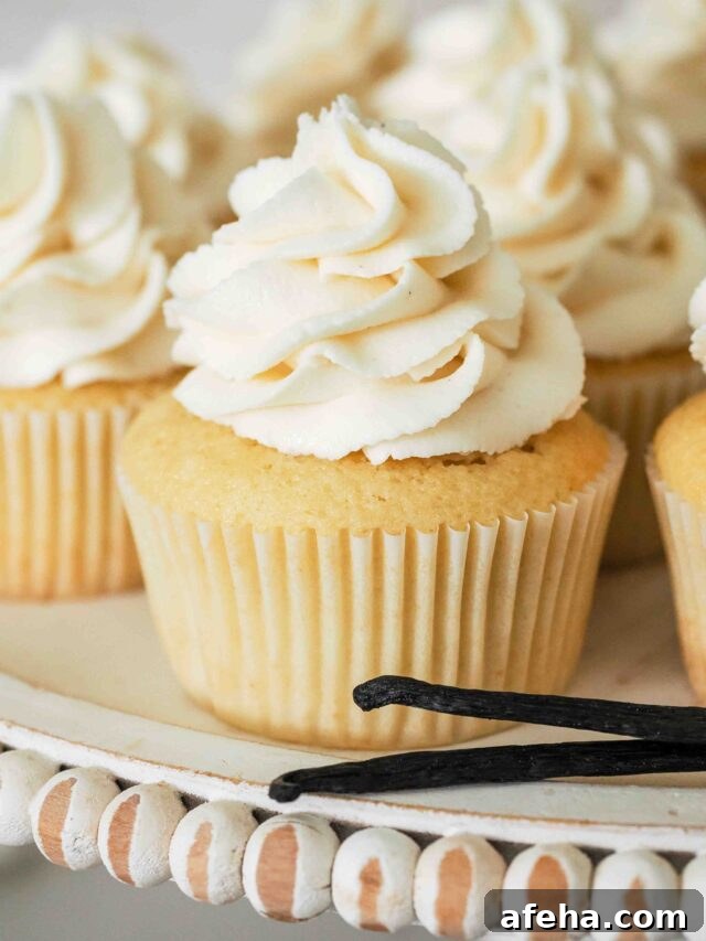 A vanilla cupcake on a cake stand with vanilla beans.