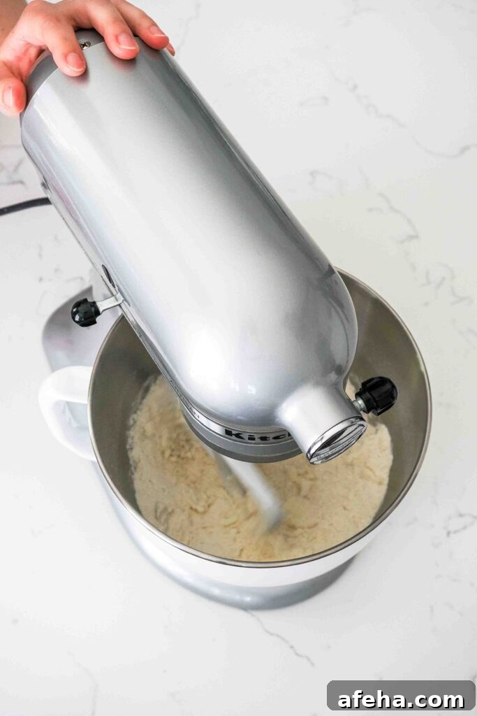 A stand mixer beats together butter, flour, sugar, baking powder, and salt.