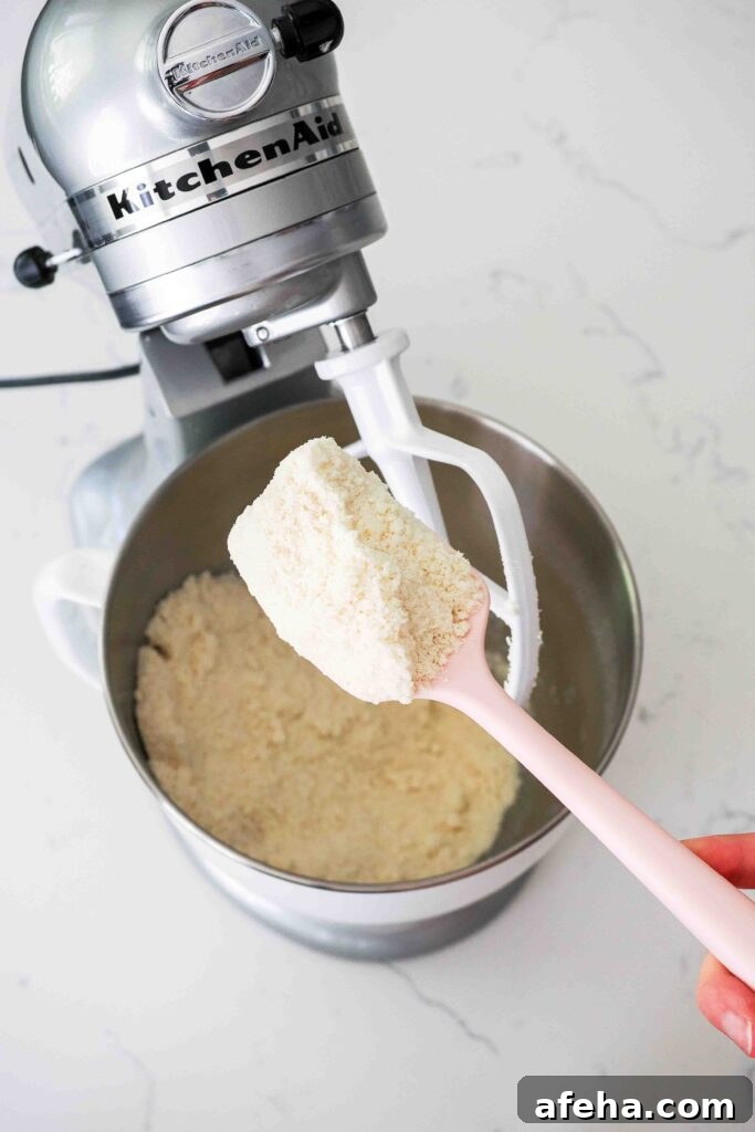A spatula holds up the creamed butter, flour, and sugar mixture.
