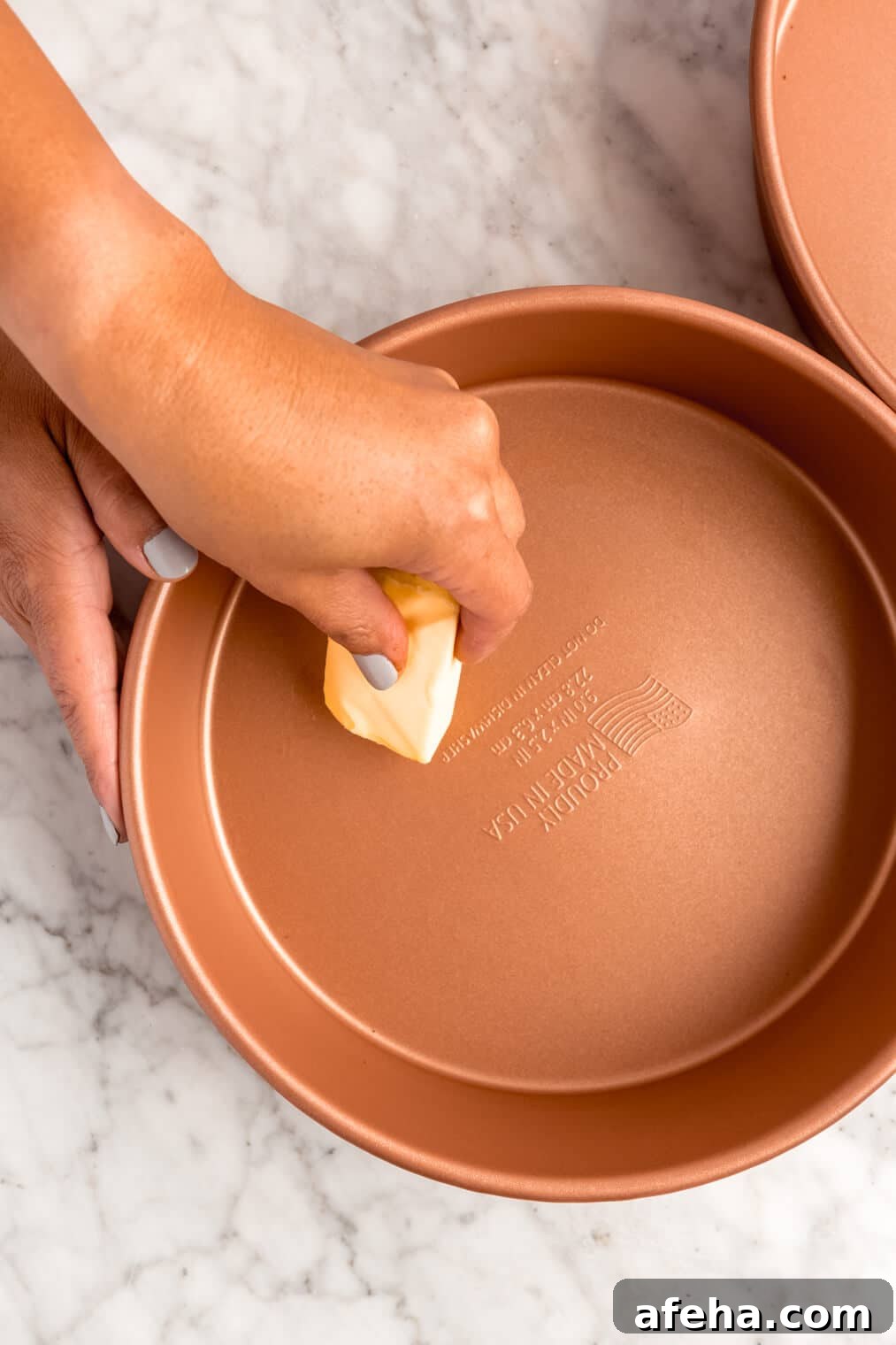 Hand buttering round cake pan.