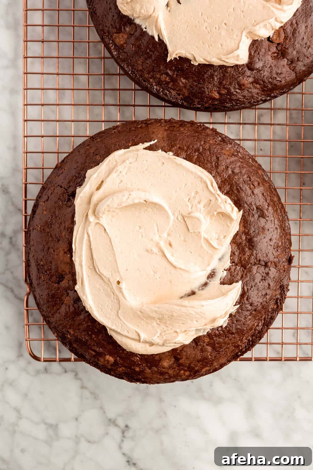 Buttercream spread on one layer of chocolate cake on a drying rack.