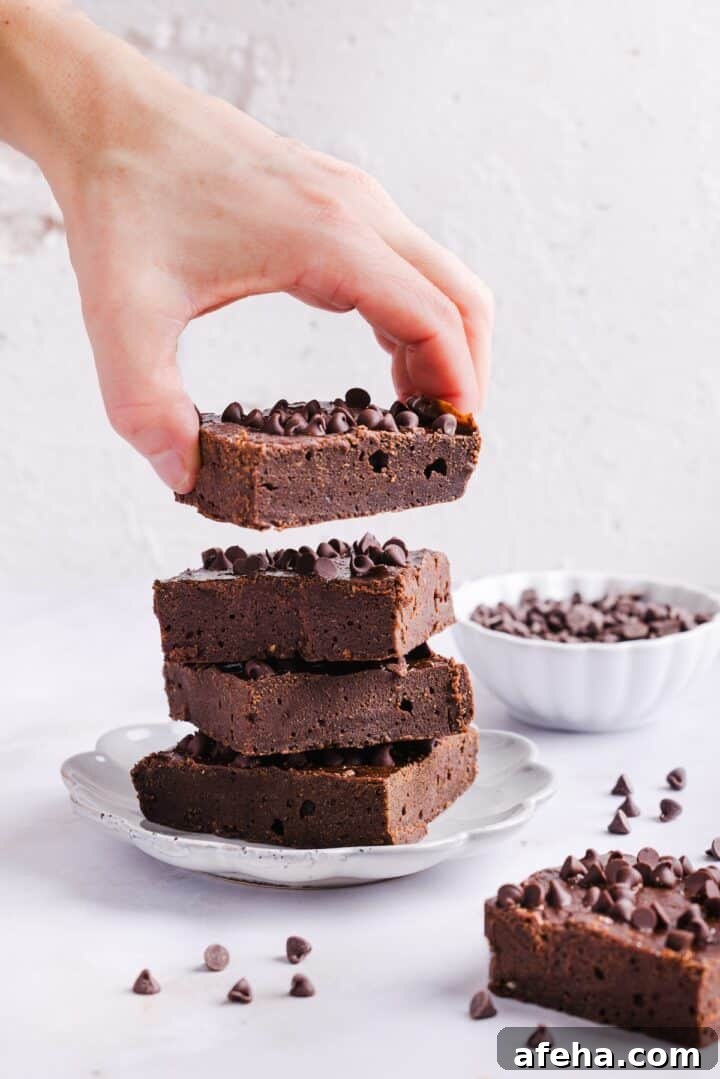 Woman's hand grabbing a cottage cheese brownie from a stack of brownies on a plate