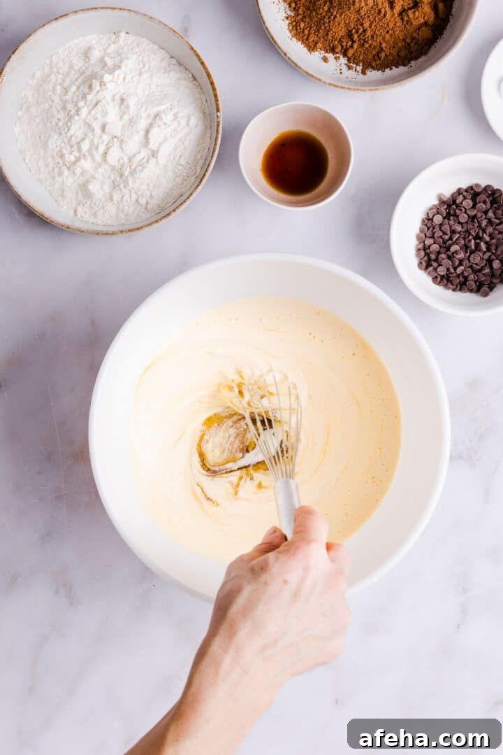 Woman's hand whisking blended cottage cheese mixture in a large white bowl