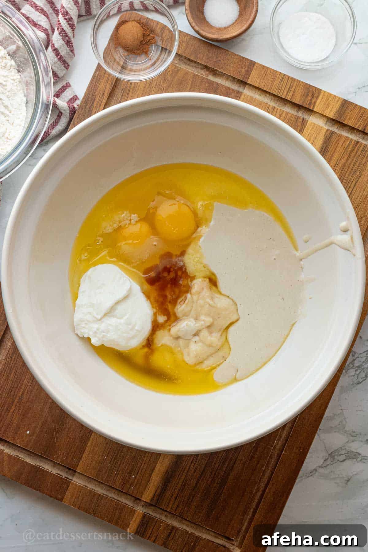 Eggs, vanilla, banana, sourdough discard, and greek yogurt in white bowl.