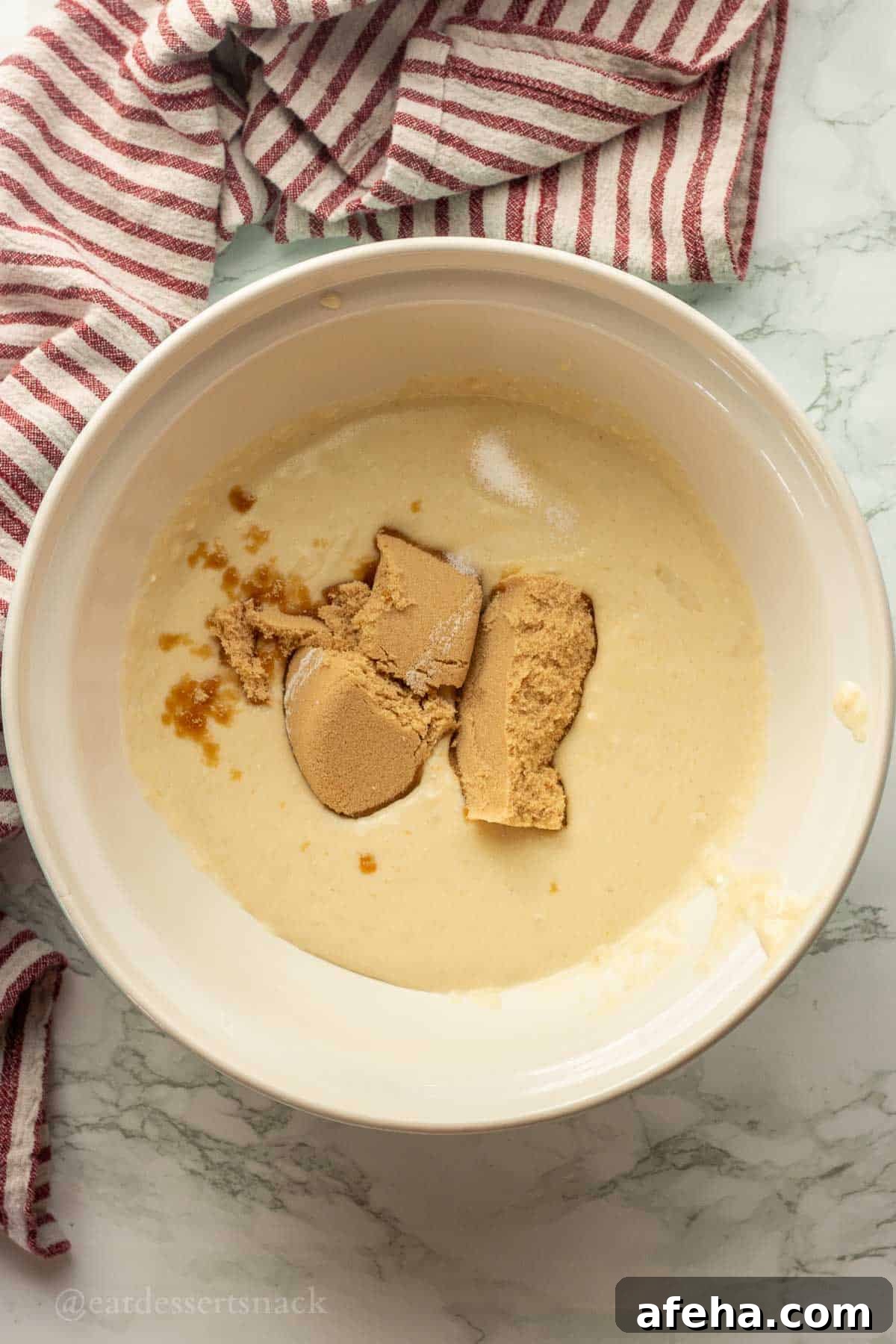 Brown sugar and salt in wet ingredients in a white bowl.