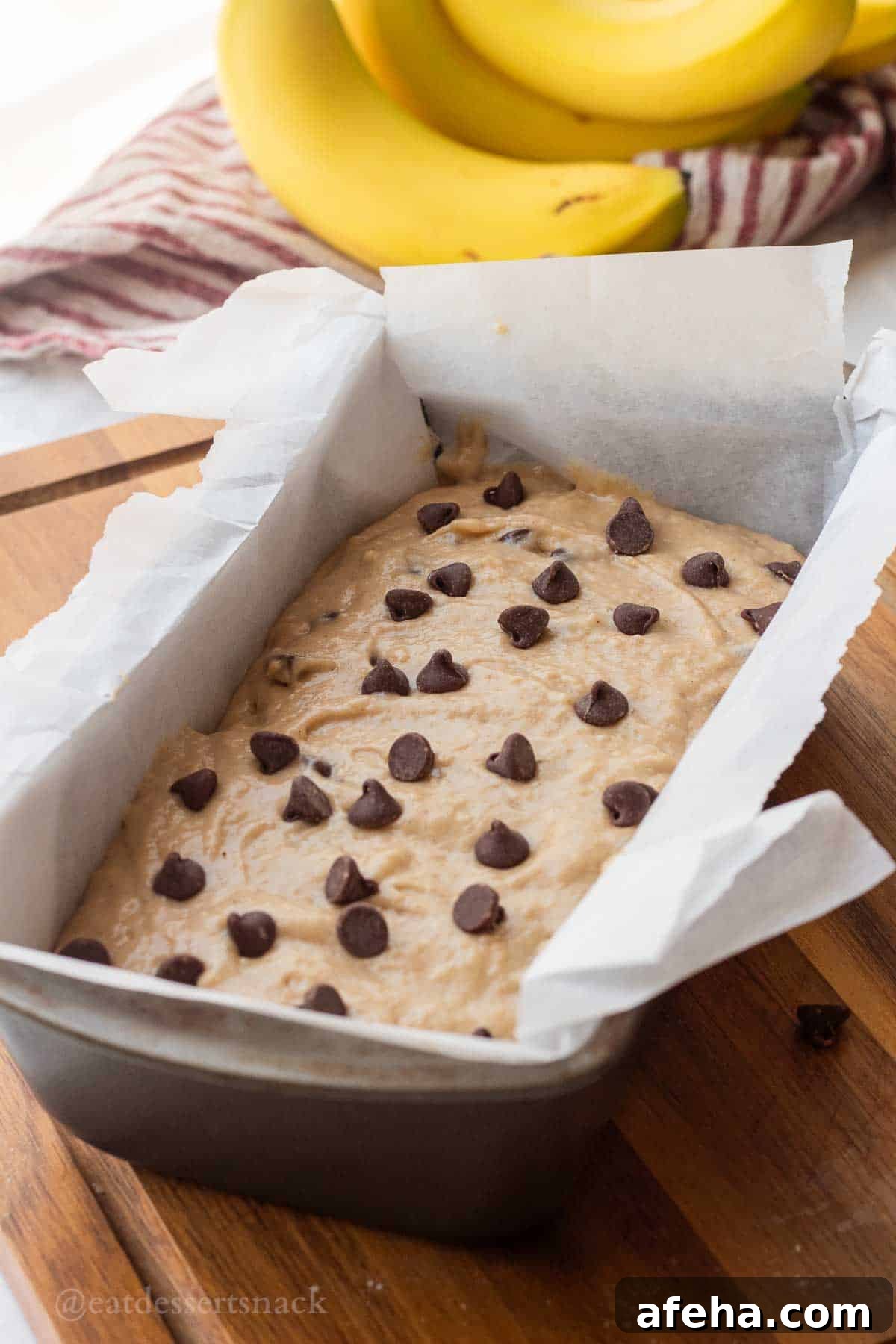 Raw banana bread batter in metal pan with parchment paper.