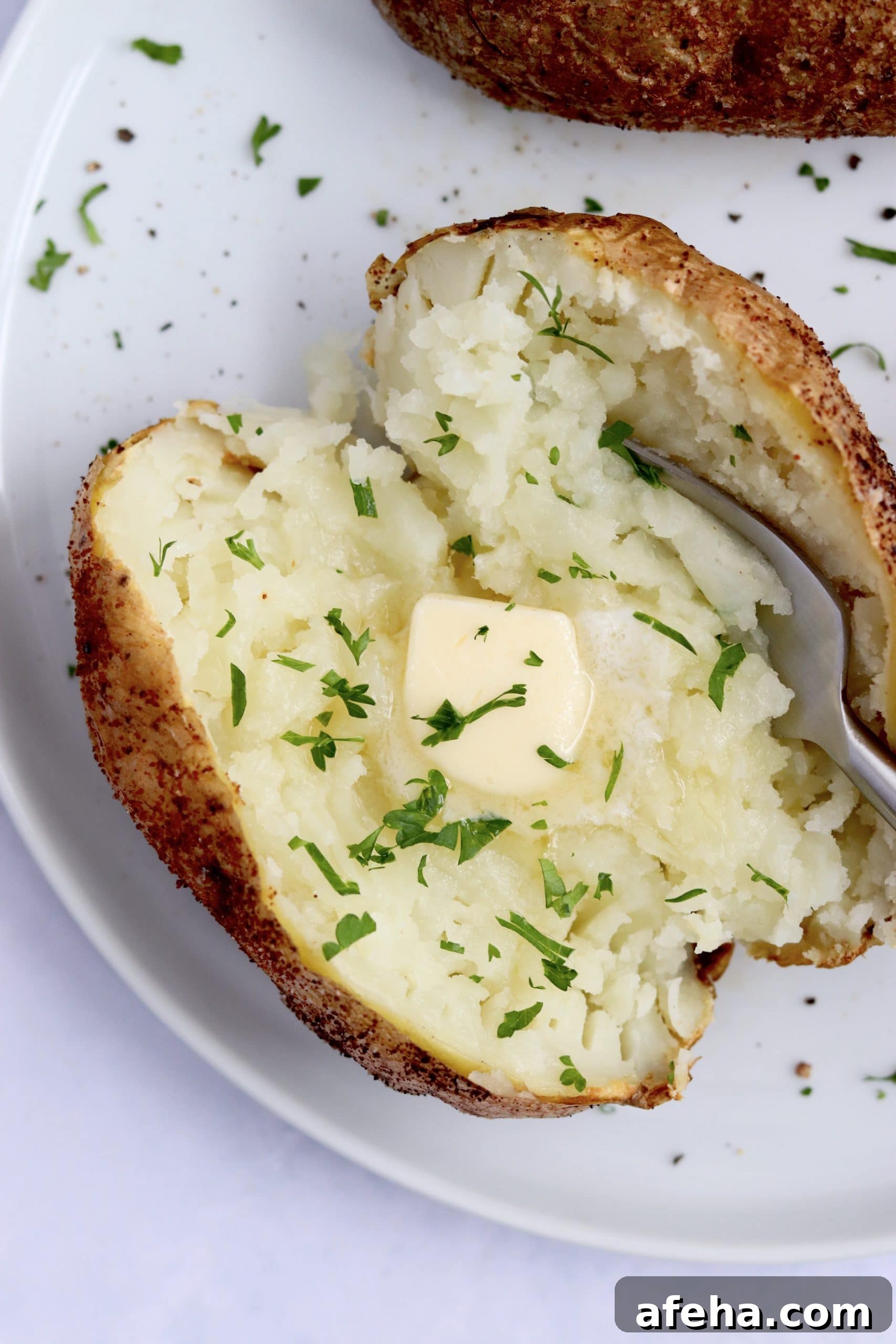 Close up of an air fryer baked potato with butter on a plate