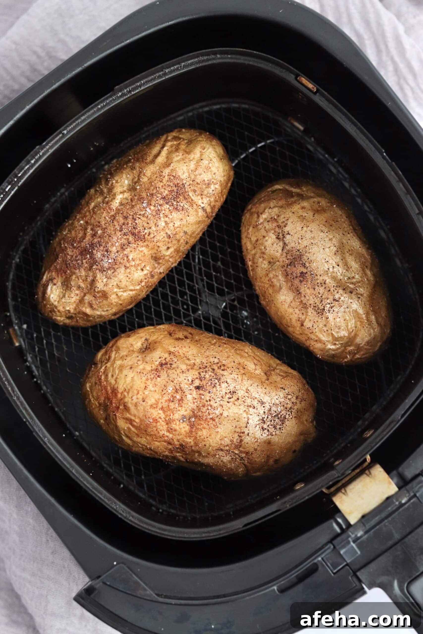 Three baked potatoes in an air fryer