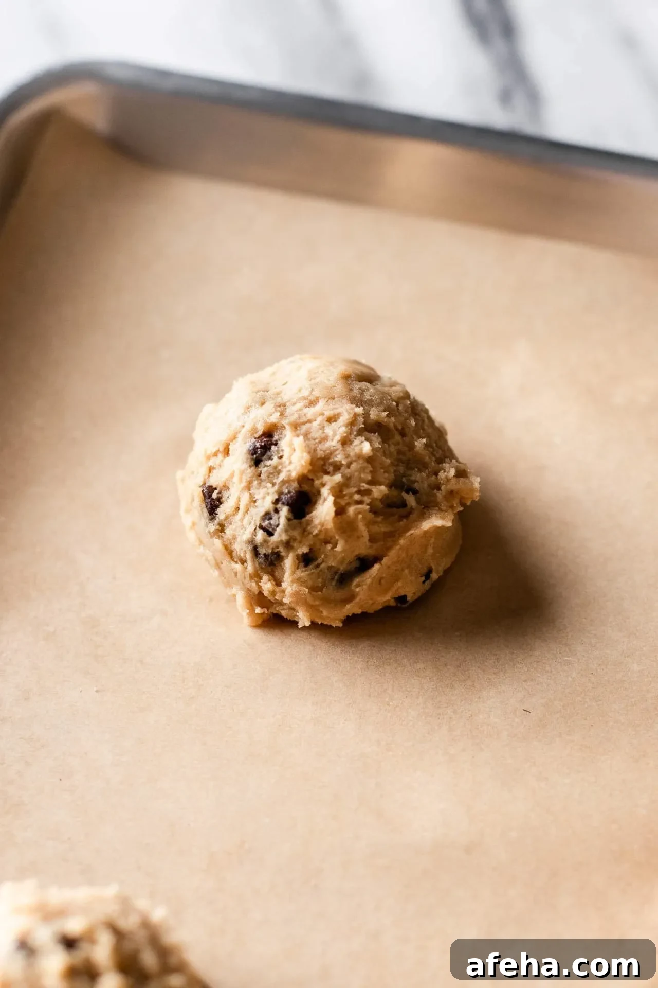 eggless chocolate chip cookie dough ball on parchment lined baking sheet