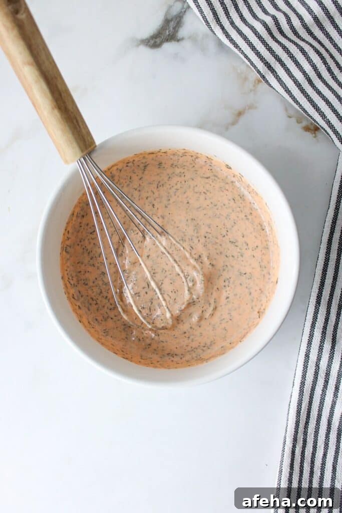 Buffalo ranch sauce in a white bowl with a whisk.