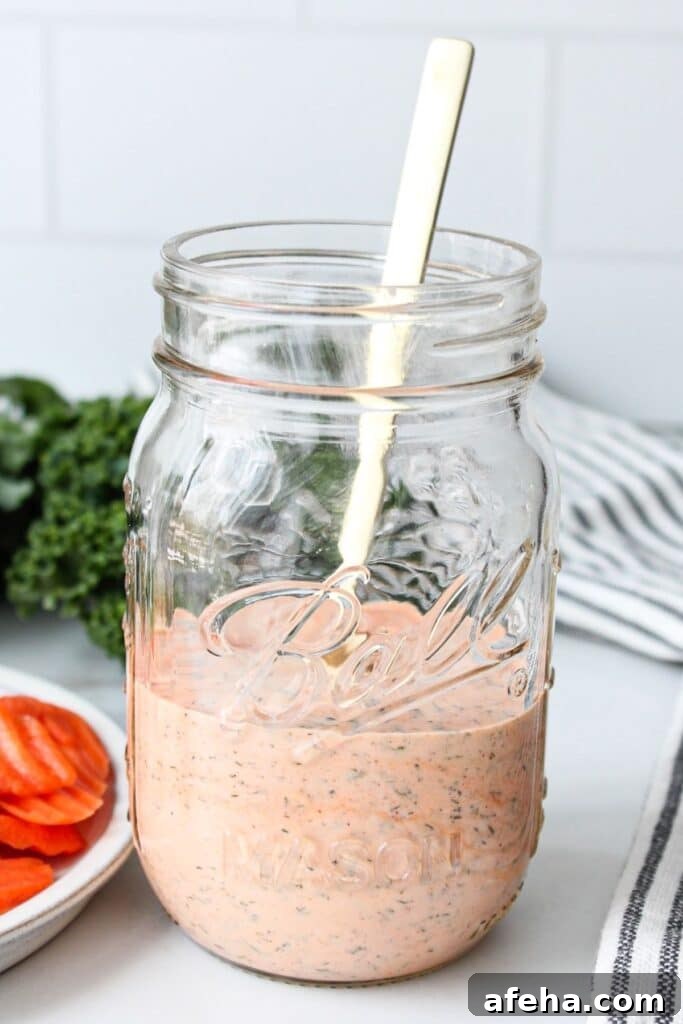 A clear mason jar of buffalo ranch sauce with a spoon.