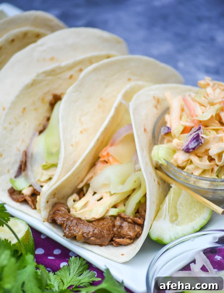 a row of korean steak tacos on a white serving platter
