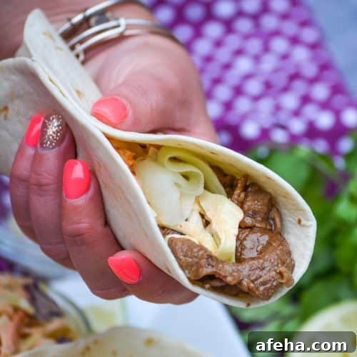 a hand holding up a korean stuffed taco in a flour tortilla