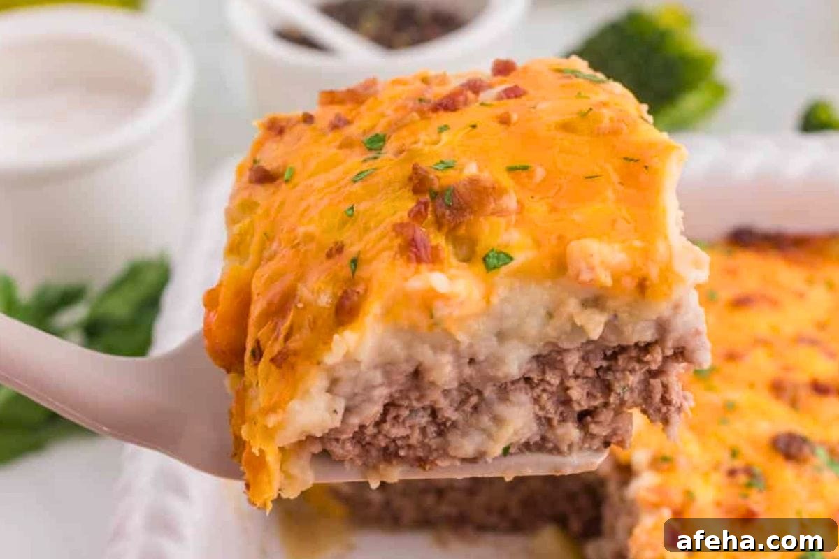 A slice of cheesy meatloaf casserole with a golden top on a spatula.