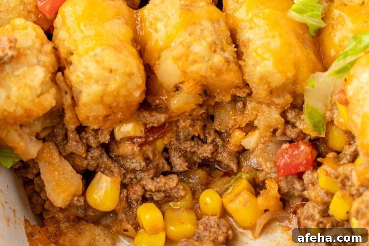 Cheesy tater tot casserole with ground beef, corn, and tomatoes.