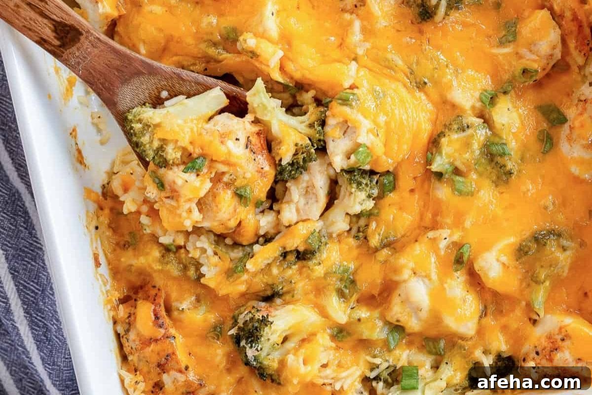 Cheesy chicken and broccoli casserole with rice being served from a white dish.