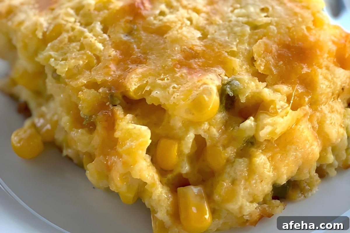A slice of jiffy corn pudding on a white plate with corn kernels and cheese.