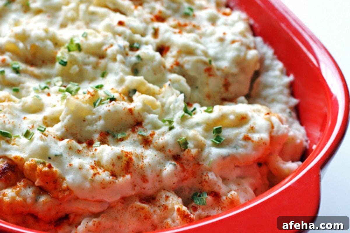 A bowl of fluffy mashed potatoes topped with chives and paprika in a vibrant dish.