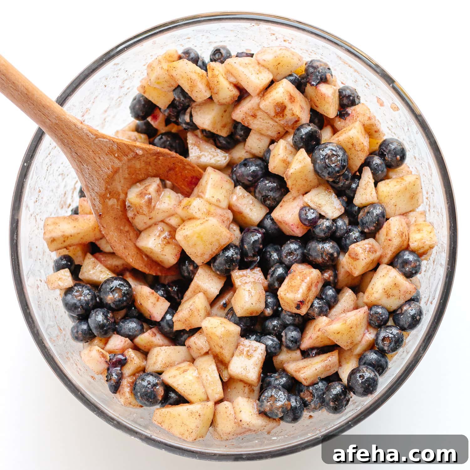 Glass bowl of blueberry and apple crumble fruit mixture.