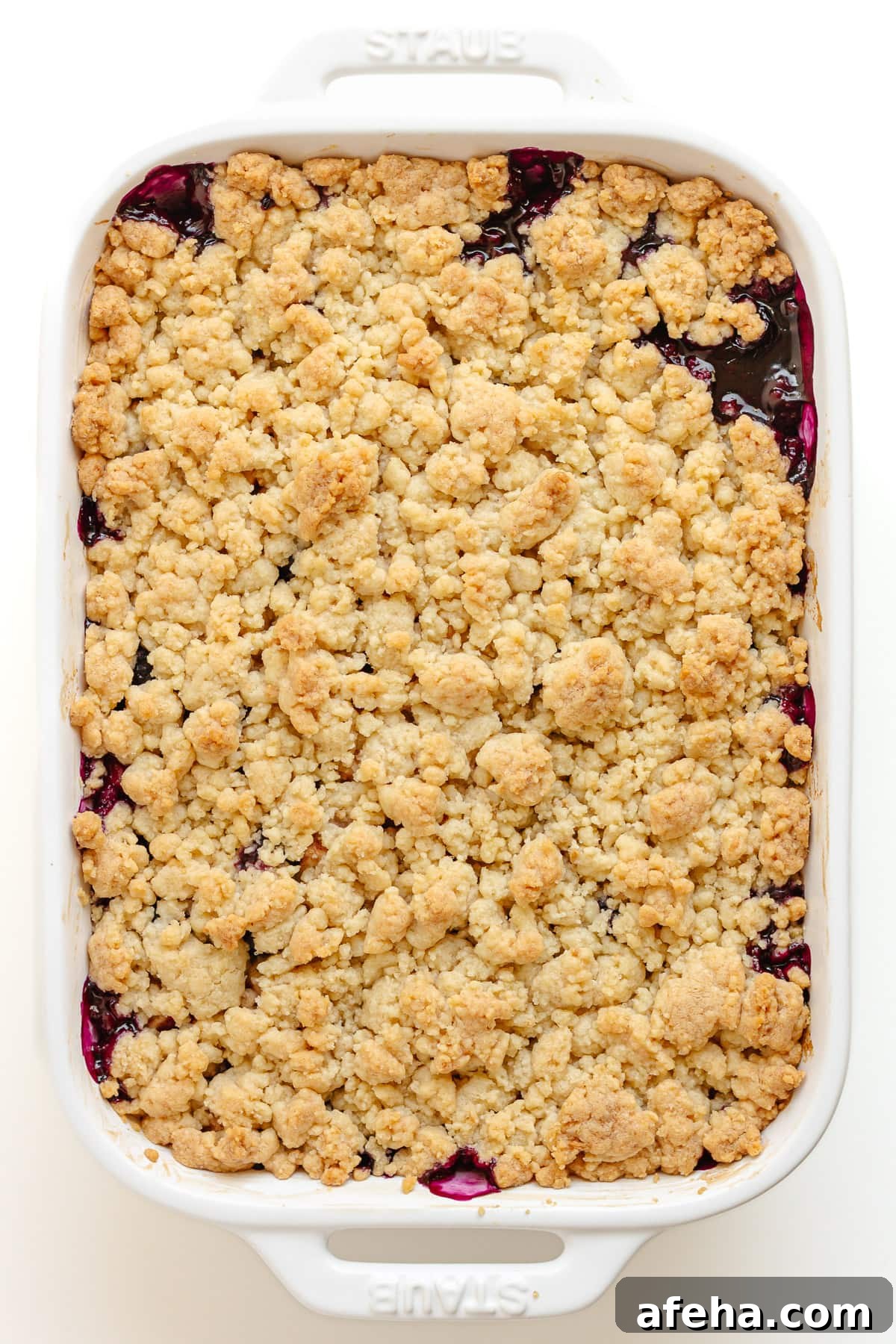 Finished baked blueberry apple crumble in white baking dish.